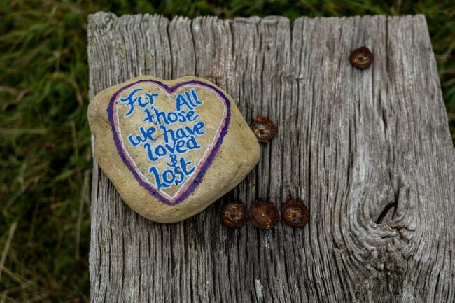 A pebble painted with the words, For all those we have loved and lost.