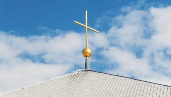 a cross on top of a building with a blue sky in the background